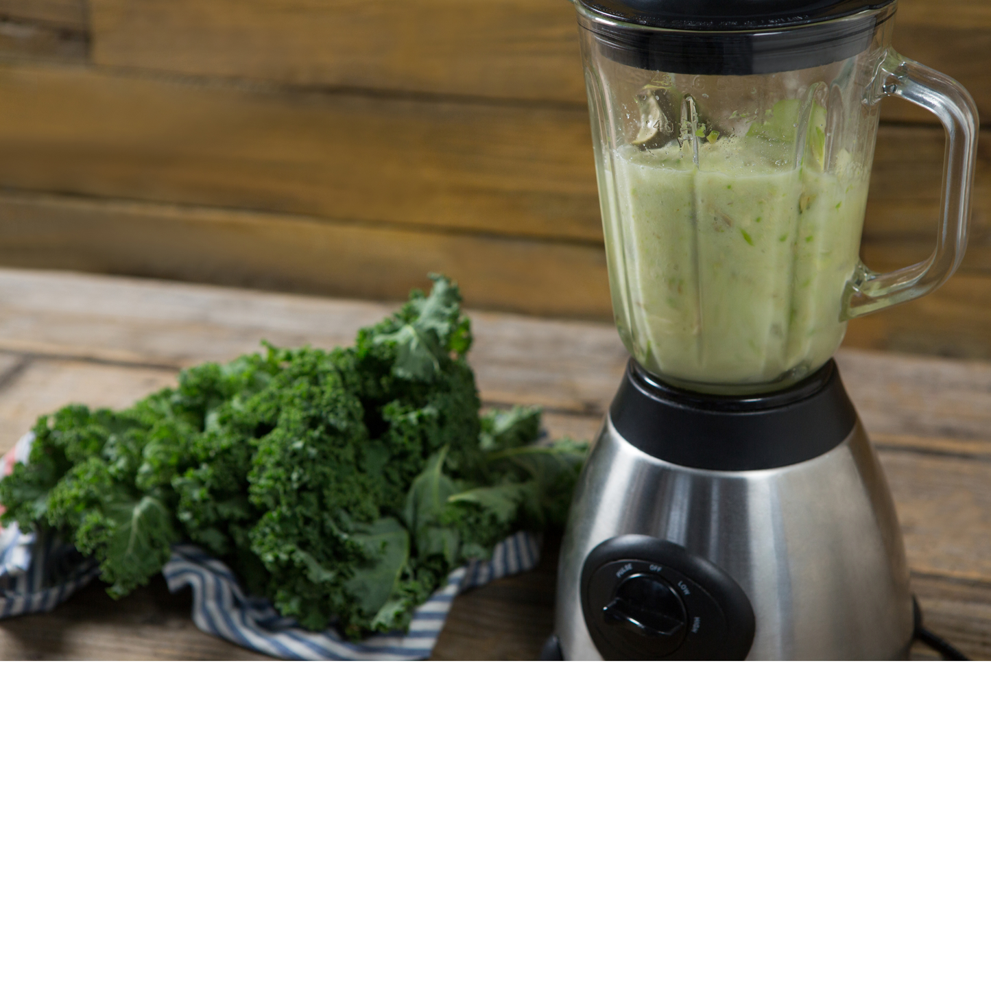 Mustard greens next to a blender filled with a green smoothie