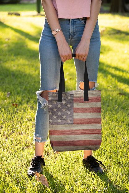 woman wearing blue jeans ripped at the knees carrying an American flag print tote bag