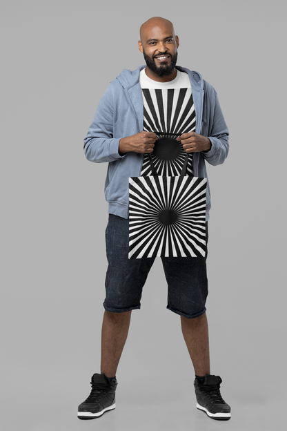 Man holding a black and white hypnotizing stripe tote bag with matching t shirt