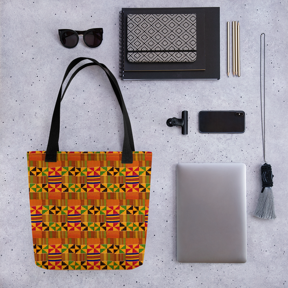 Kente cloth tote bag on a table with sunglasses and a computer