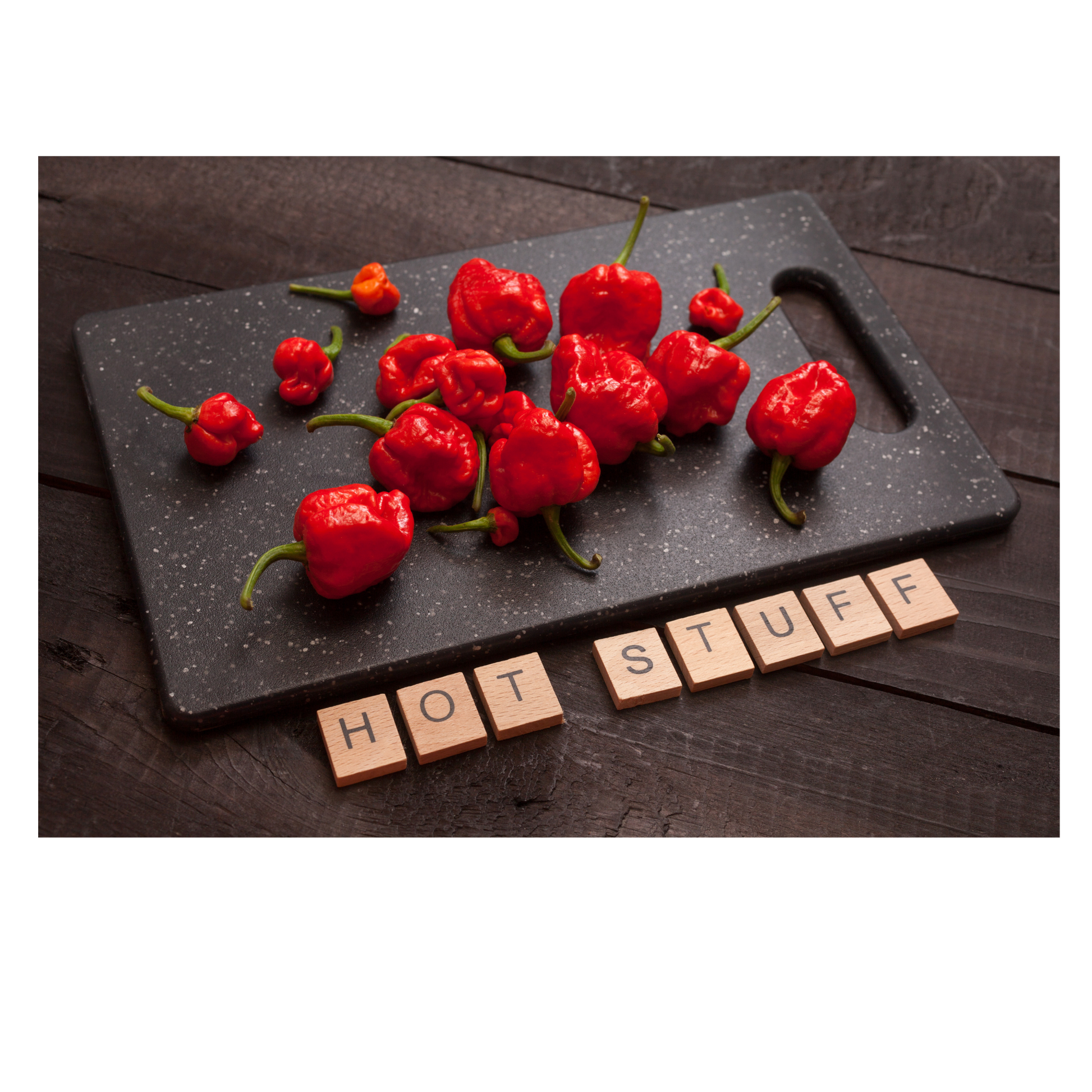 red scorpion peppers on a black cutting board with wooden block letters that spell out HOT STUFF