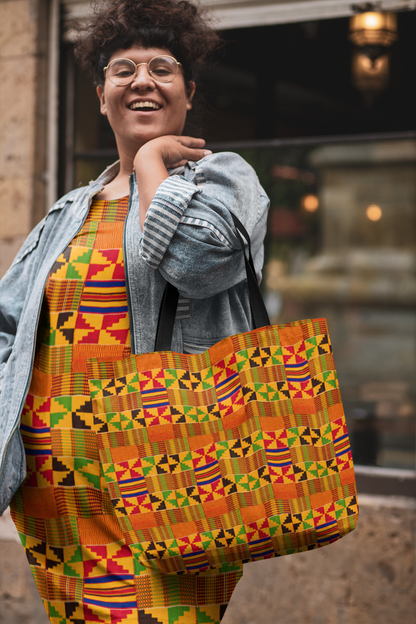 Plus size woman wearing a Kente cloth dress with a denim jakcet and Kente cloth tote bag over her shoulder